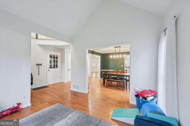 living room featuring baseboards, high vaulted ceiling, and wood finished floors