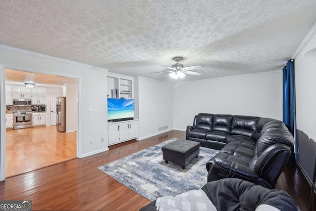 living area with ceiling fan, a textured ceiling, wood finished floors, and ornamental molding