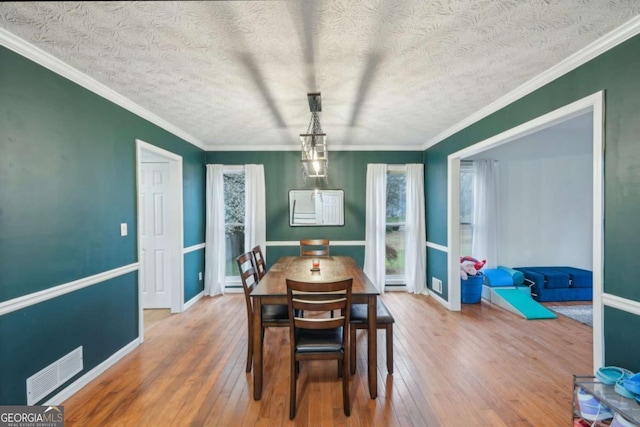 dining space with visible vents, hardwood / wood-style floors, and crown molding