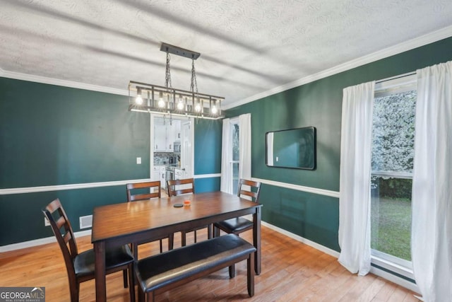 dining room featuring crown molding, wood finished floors, baseboards, and a wealth of natural light