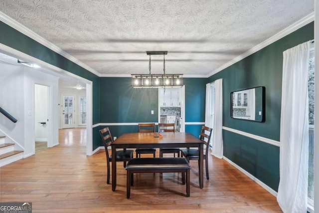 dining room featuring stairs, wood finished floors, baseboards, and ornamental molding