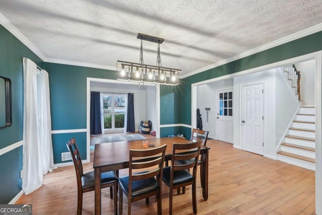 dining room featuring a textured ceiling, stairway, wood finished floors, and ornamental molding