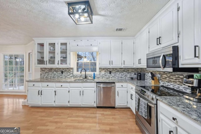 kitchen with a sink, stainless steel appliances, visible vents, and white cabinets