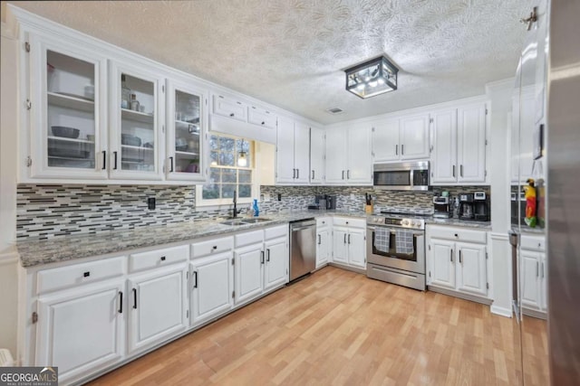 kitchen featuring a sink, white cabinets, light wood finished floors, and stainless steel appliances