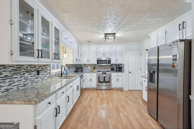 kitchen with white cabinets, appliances with stainless steel finishes, light wood-style floors, and a sink