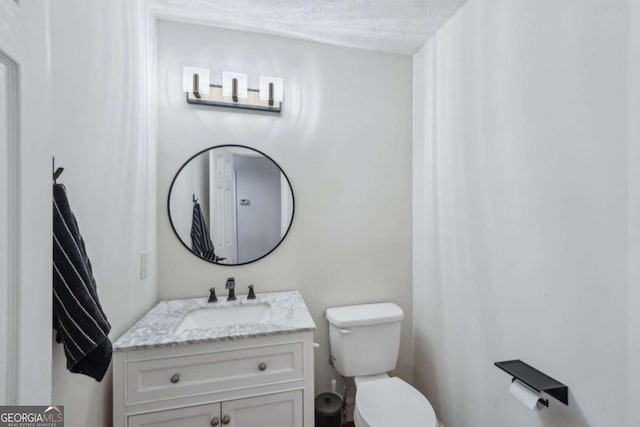 bathroom featuring toilet, vanity, and a textured ceiling