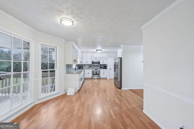 kitchen with white cabinetry, crown molding, light wood-style floors, and appliances with stainless steel finishes