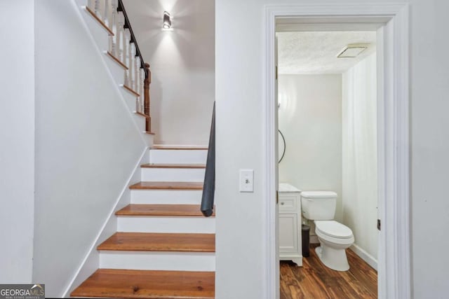 staircase with baseboards, a textured ceiling, and wood finished floors