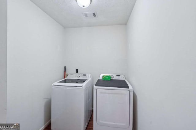 washroom with visible vents, laundry area, washer and dryer, a textured ceiling, and dark wood-style flooring