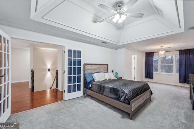 carpeted bedroom with a raised ceiling, french doors, visible vents, and baseboards