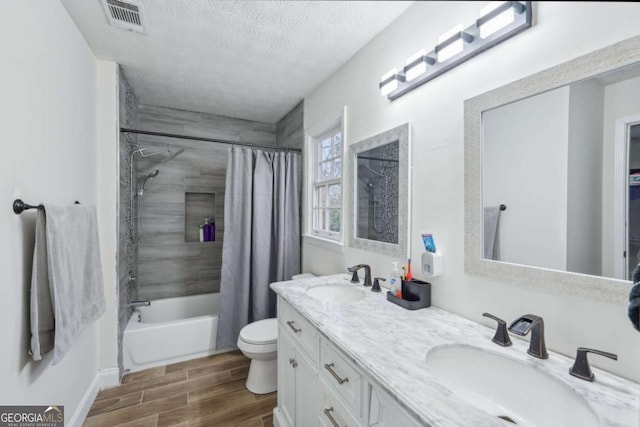 bathroom featuring a sink, visible vents, a textured ceiling, and wood tiled floor