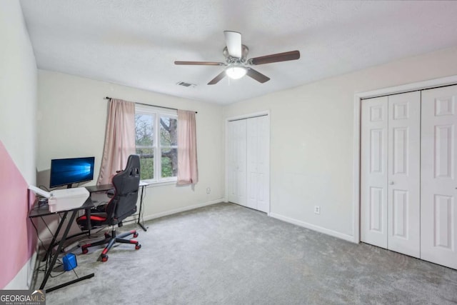 carpeted office with visible vents, baseboards, a textured ceiling, and a ceiling fan