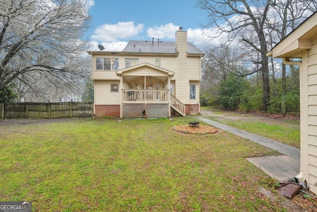 back of property featuring a fire pit, a chimney, a yard, and fence