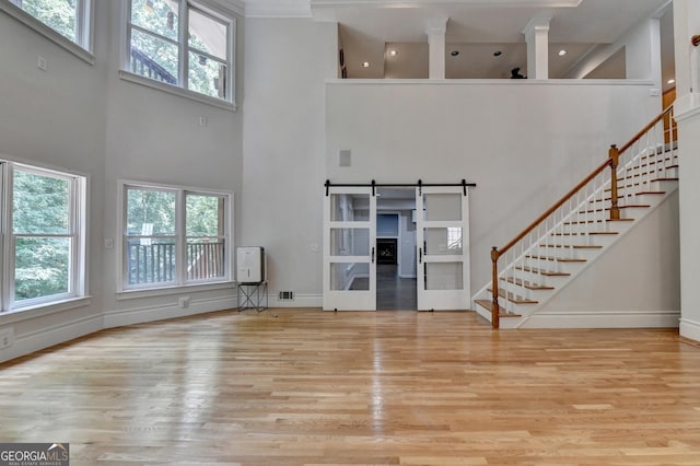 unfurnished living room featuring a barn door, plenty of natural light, and wood finished floors