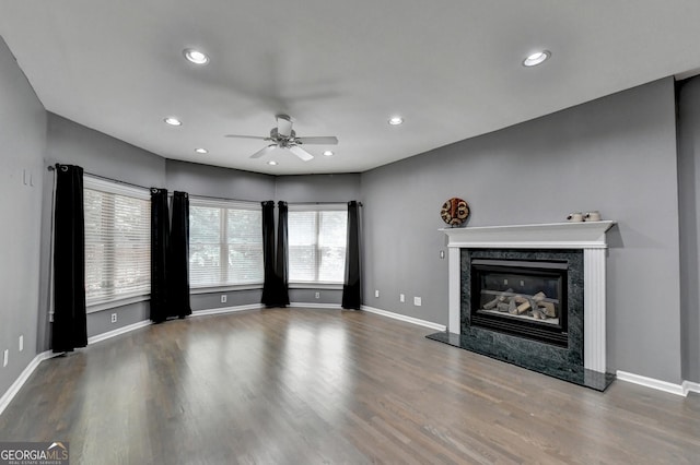 unfurnished living room featuring recessed lighting, wood finished floors, baseboards, and a high end fireplace