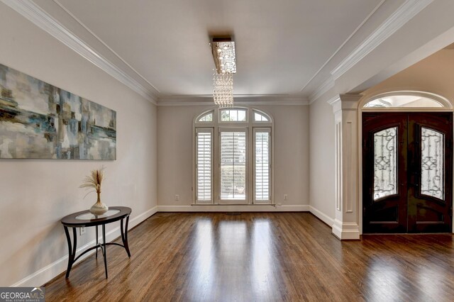 foyer entrance featuring french doors, a notable chandelier, wood finished floors, and ornamental molding