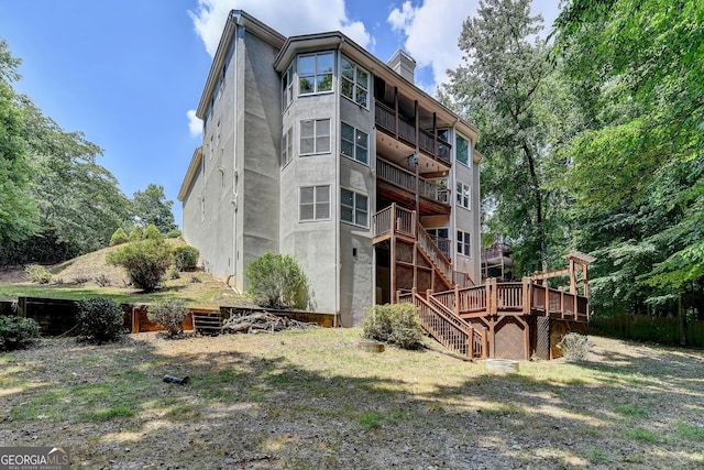 back of property featuring stairway, a chimney, and a deck