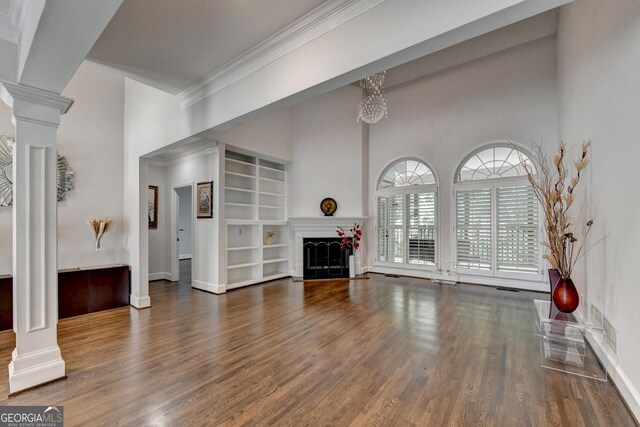 living room featuring ornamental molding, wood finished floors, a fireplace, baseboards, and ornate columns