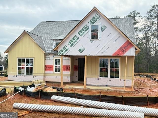 rear view of property featuring board and batten siding and roof with shingles