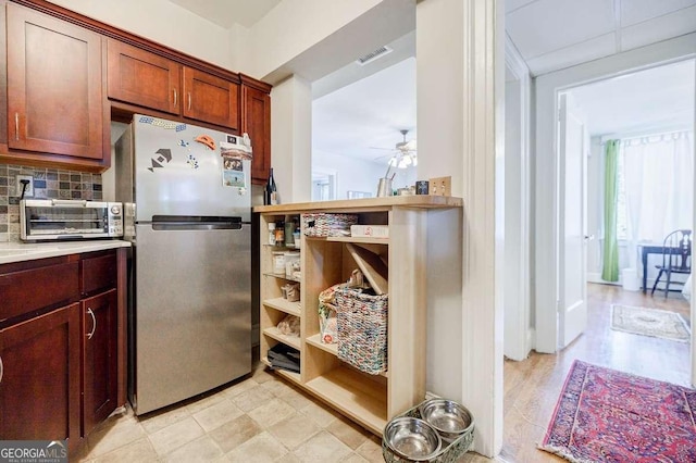 kitchen with visible vents, backsplash, ceiling fan, light countertops, and freestanding refrigerator