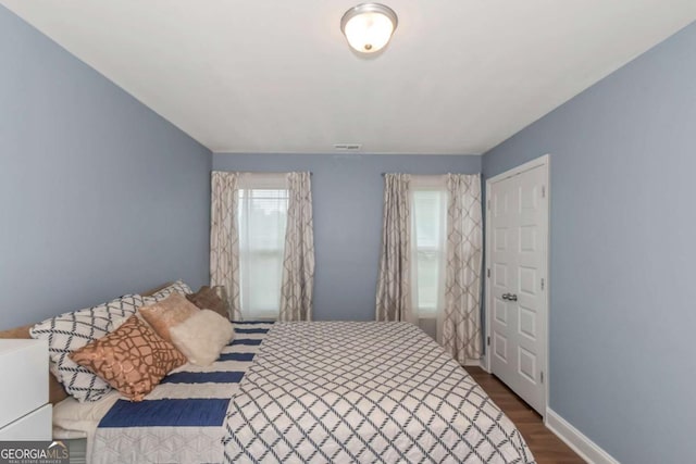 bedroom with baseboards and dark wood-type flooring