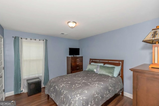 bedroom with visible vents, baseboards, and wood finished floors