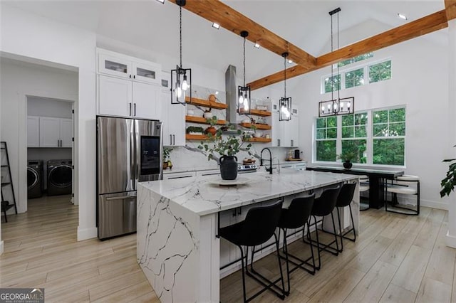 kitchen with open shelves, stainless steel fridge with ice dispenser, washer and dryer, beamed ceiling, and backsplash