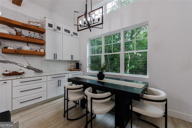 dining area with baseboards, light wood-type flooring, and a chandelier