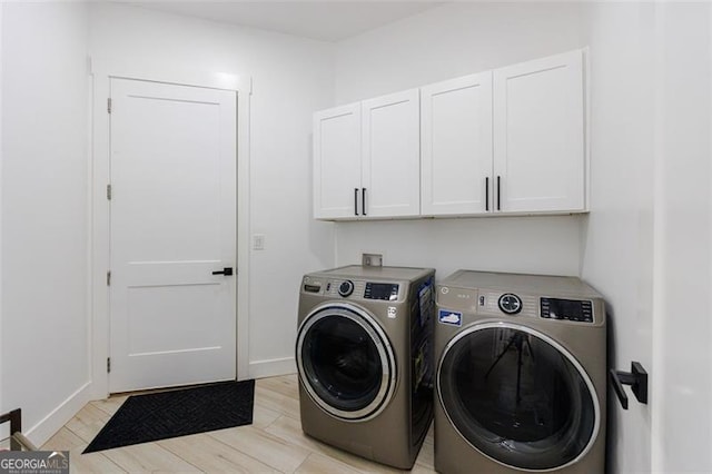 clothes washing area featuring light wood-style flooring, cabinet space, baseboards, and washer and clothes dryer