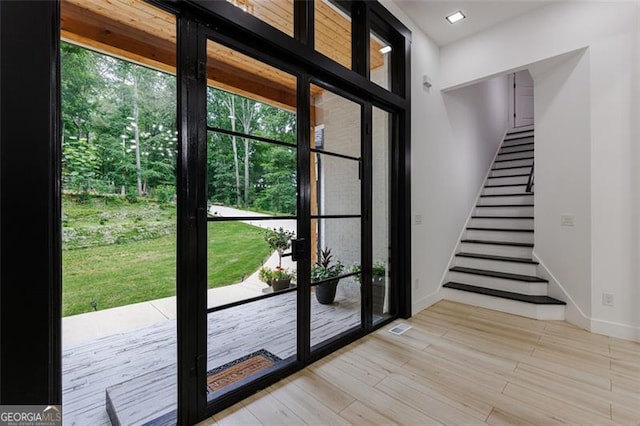 doorway with stairs, visible vents, baseboards, and light wood finished floors