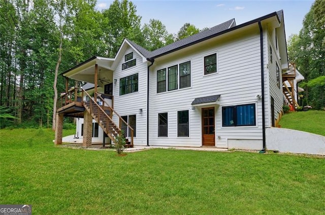 back of property featuring stairway and a lawn