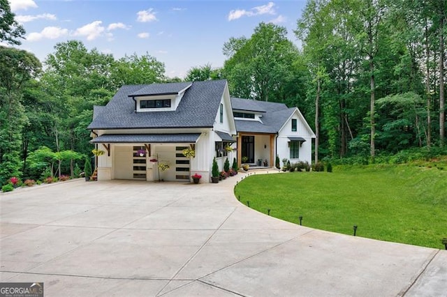 modern farmhouse with driveway, a shingled roof, and a front lawn