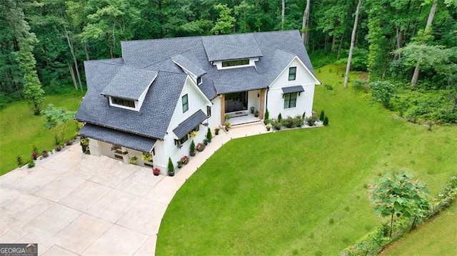 view of front of house with a front yard, concrete driveway, and a shingled roof