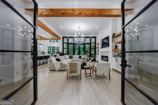 living room featuring french doors, an inviting chandelier, a glass covered fireplace, and light wood finished floors