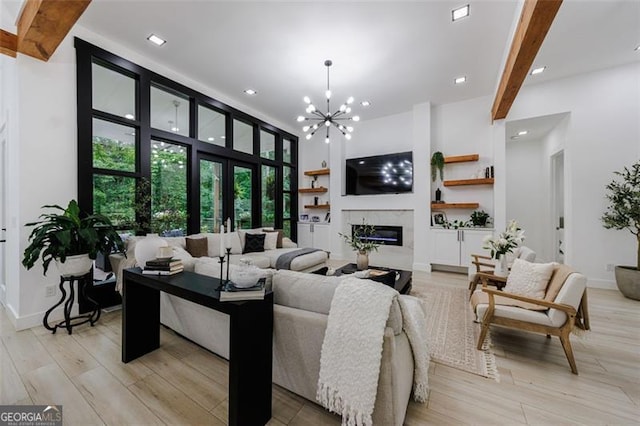 living room featuring a high end fireplace, baseboards, beamed ceiling, light wood-type flooring, and a notable chandelier