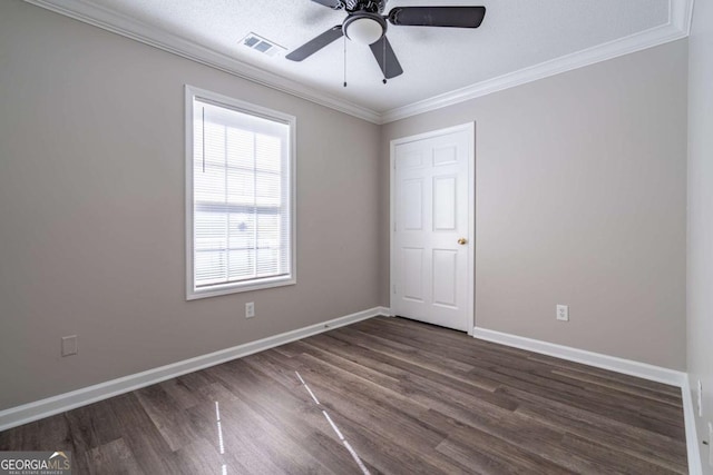 unfurnished room featuring dark wood finished floors, visible vents, baseboards, and ornamental molding