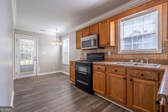 kitchen with black / electric stove, visible vents, a sink, stainless steel microwave, and brown cabinets