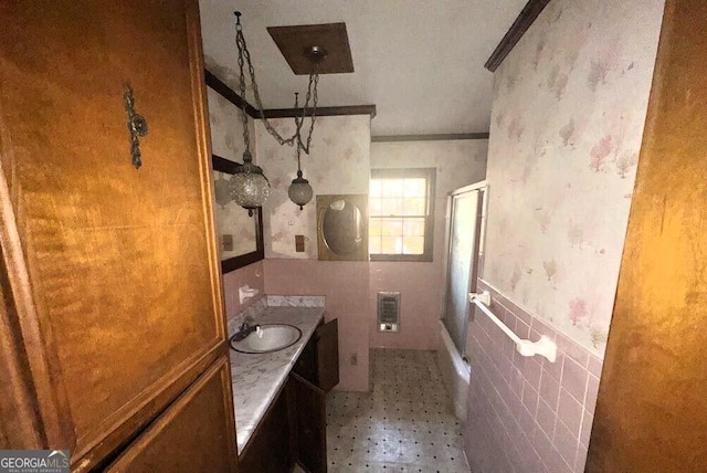 bathroom featuring an enclosed shower, tile walls, wainscoting, wallpapered walls, and vanity