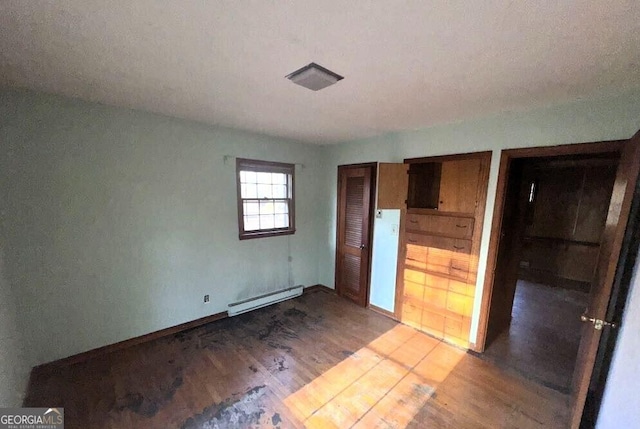 unfurnished bedroom with wood finished floors, baseboards, a closet, and a baseboard radiator