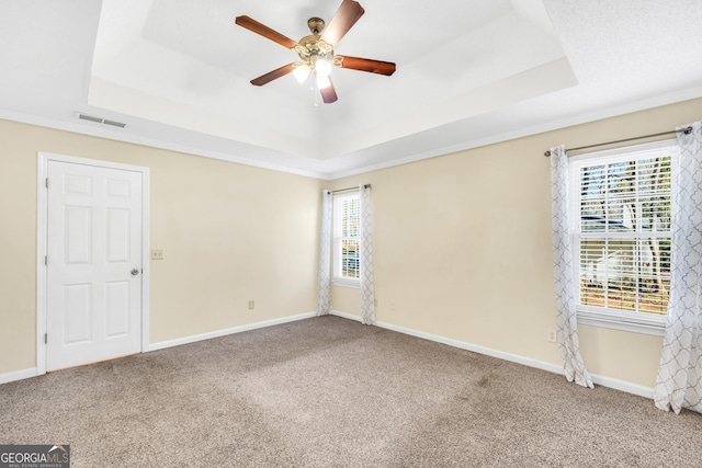 unfurnished room with visible vents, carpet flooring, and a tray ceiling