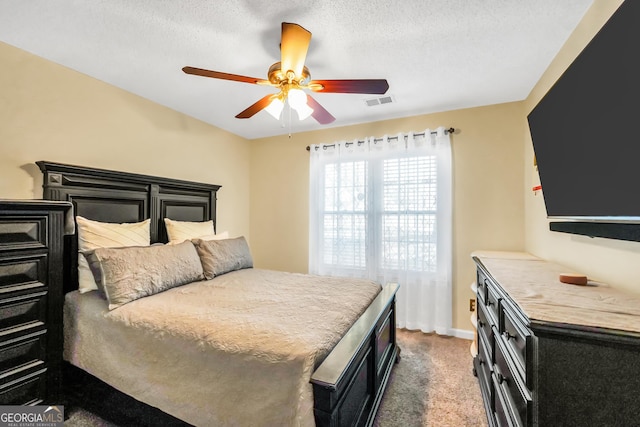 carpeted bedroom featuring baseboards, visible vents, a textured ceiling, and ceiling fan