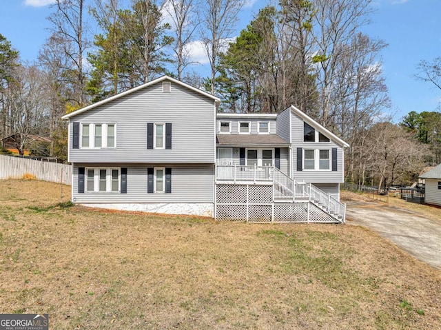 back of property with stairway, a lawn, a porch, and fence