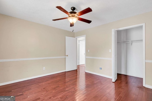 unfurnished bedroom with a closet, baseboards, a textured ceiling, and hardwood / wood-style flooring