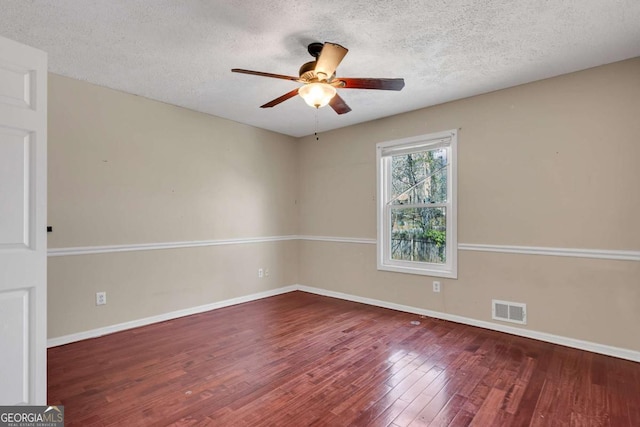 empty room featuring baseboards, wood finished floors, visible vents, and ceiling fan