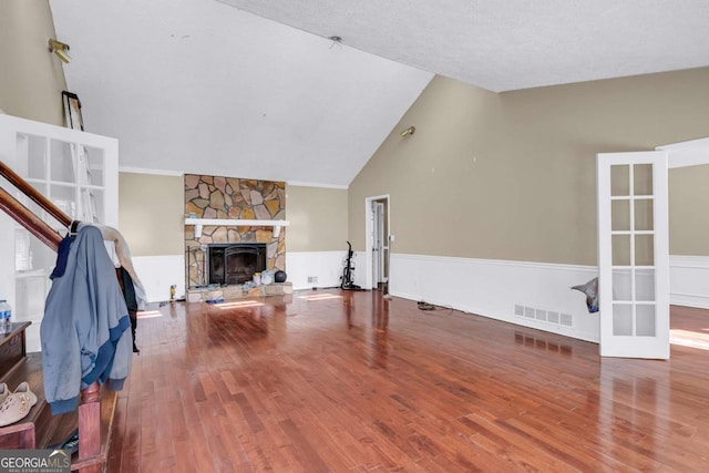 living area with visible vents, a fireplace, french doors, wood finished floors, and high vaulted ceiling