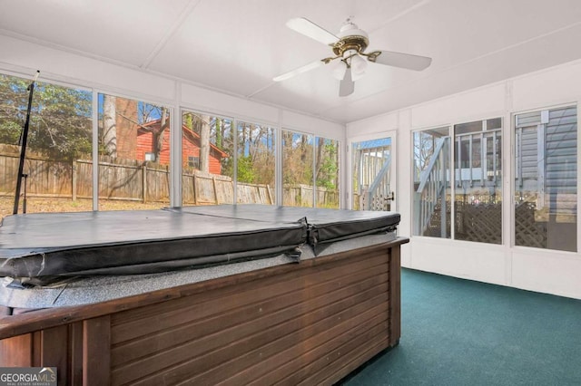 unfurnished sunroom with ceiling fan, a wealth of natural light, and a hot tub