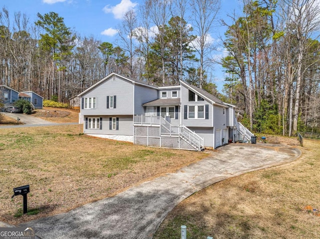 view of front of home featuring a garage, a front lawn, concrete driveway, and stairs