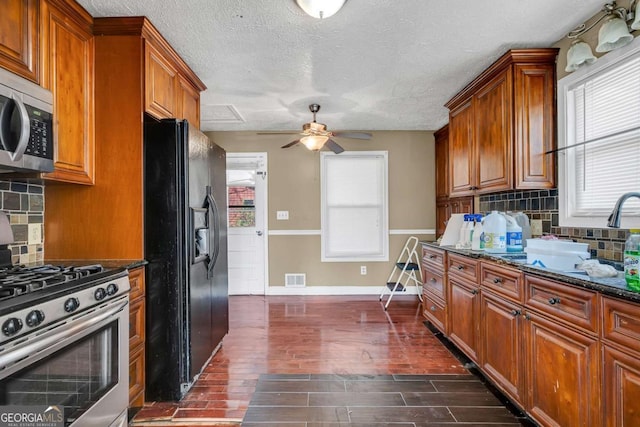 kitchen featuring a sink, stainless steel appliances, brown cabinets, and dark wood-type flooring