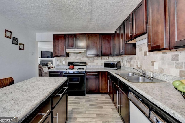 kitchen featuring under cabinet range hood, range with gas stovetop, light countertops, and a sink