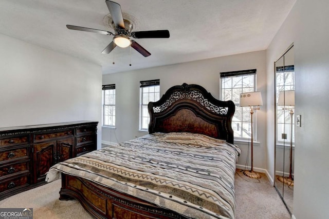 bedroom featuring light colored carpet, baseboards, and ceiling fan